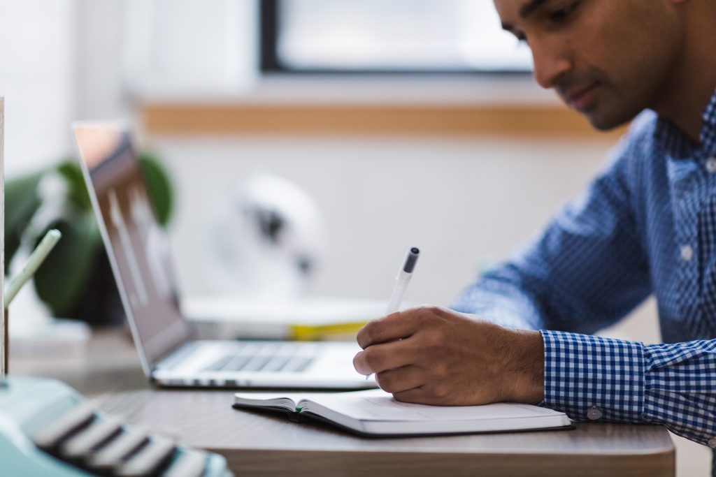 Image of person at a desk looking thoughtfully at a notepad writing notes, with a laptop in front of him. Image is to convey the thoughtfulness Canadian Viewpoint applies to their client engagements.